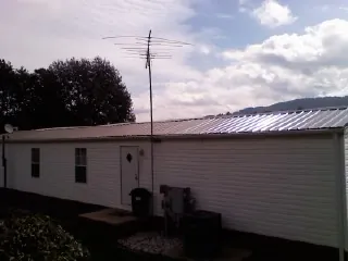 New metal roof on a single wide mobile home with a TV antenna in Arlington